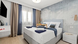 A modern hotel room with a large bed, a bedside table, a flat-screen TV, and a view of the city. - Casa Dika Pool & Lounge, Barban, Croatia (Barban)