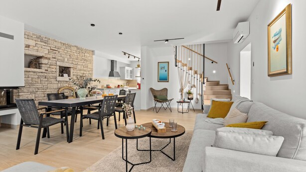 A modern living room with a grey sofa, a dining area with a black table, and a staircase leading to an upper level. - Casa Dika Pool & Lounge, Barban, Croatia (Barban)