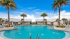 A large, clear swimming pool with palm trees and lounge chairs around it, surrounded by buildings. - Town of Prominence 67C - Pour Beach Life (Santa Rosa Beach)