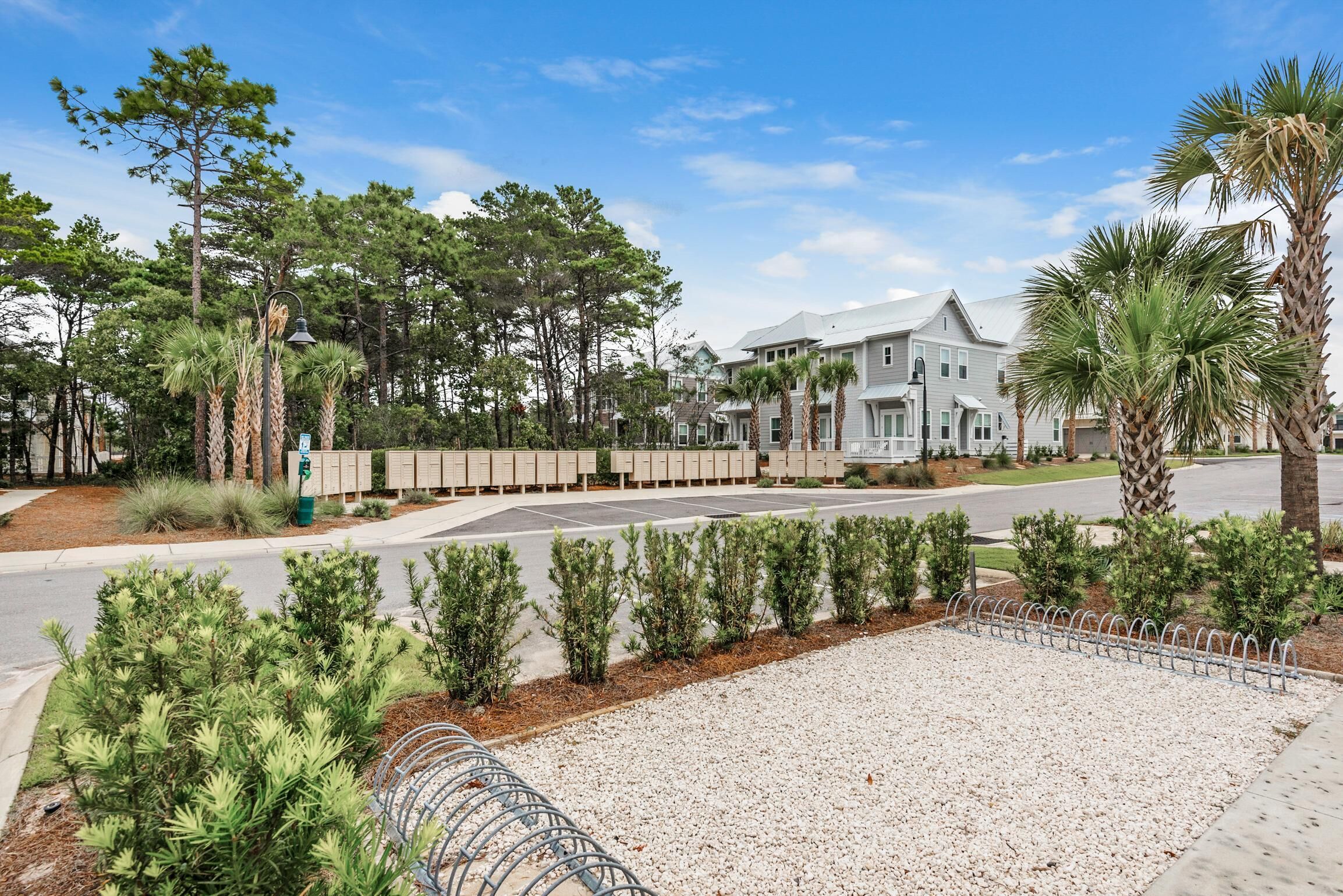 A residential area with a row of houses, a street, and a gravel area with a metal fence.