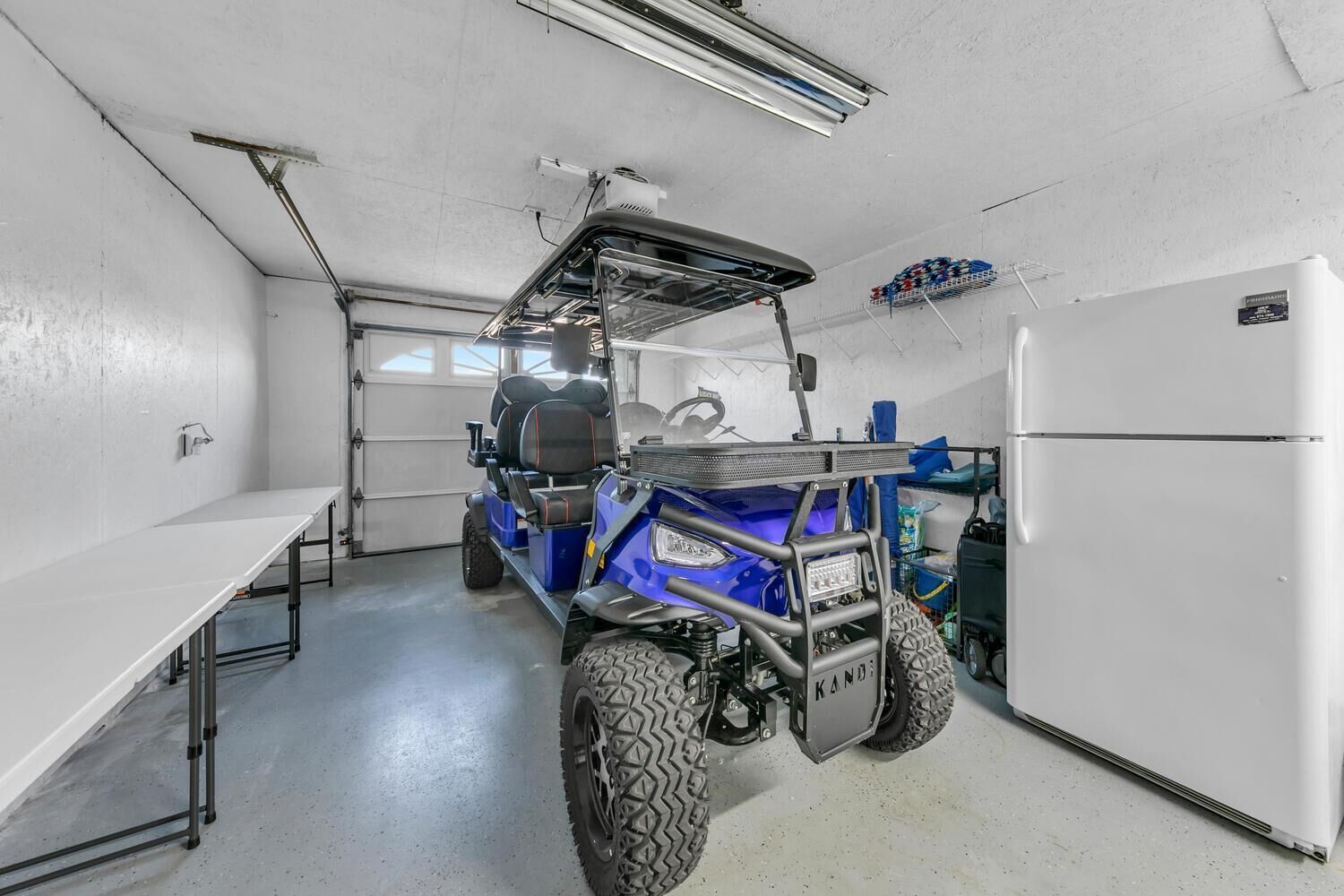 Una cocina compacta con un refrigerador blanco, un carrito azul y una encimera blanca.