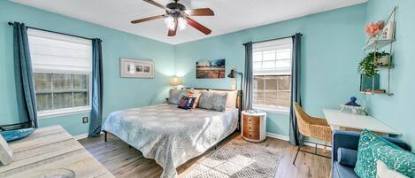 Une chambre à coucher avec un lit, un bureau, une chaise, un ventilateur de plafond et une fenêtre.