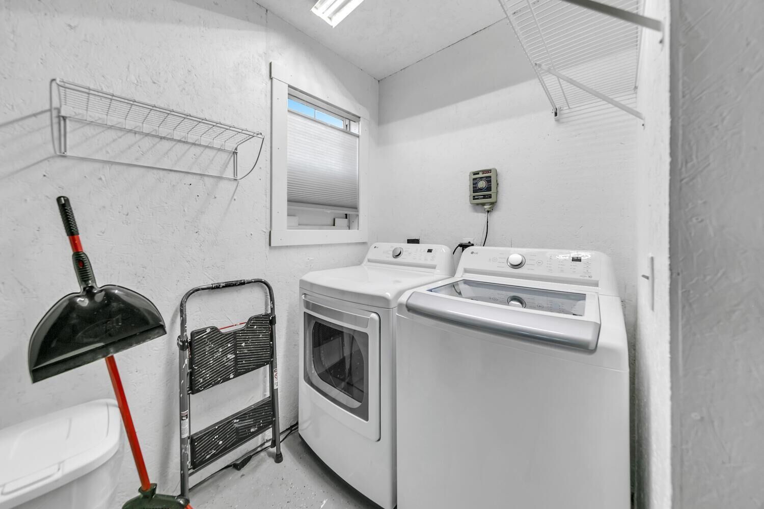 Una sala de lavandería con lavadora, secadora y un trapeador.