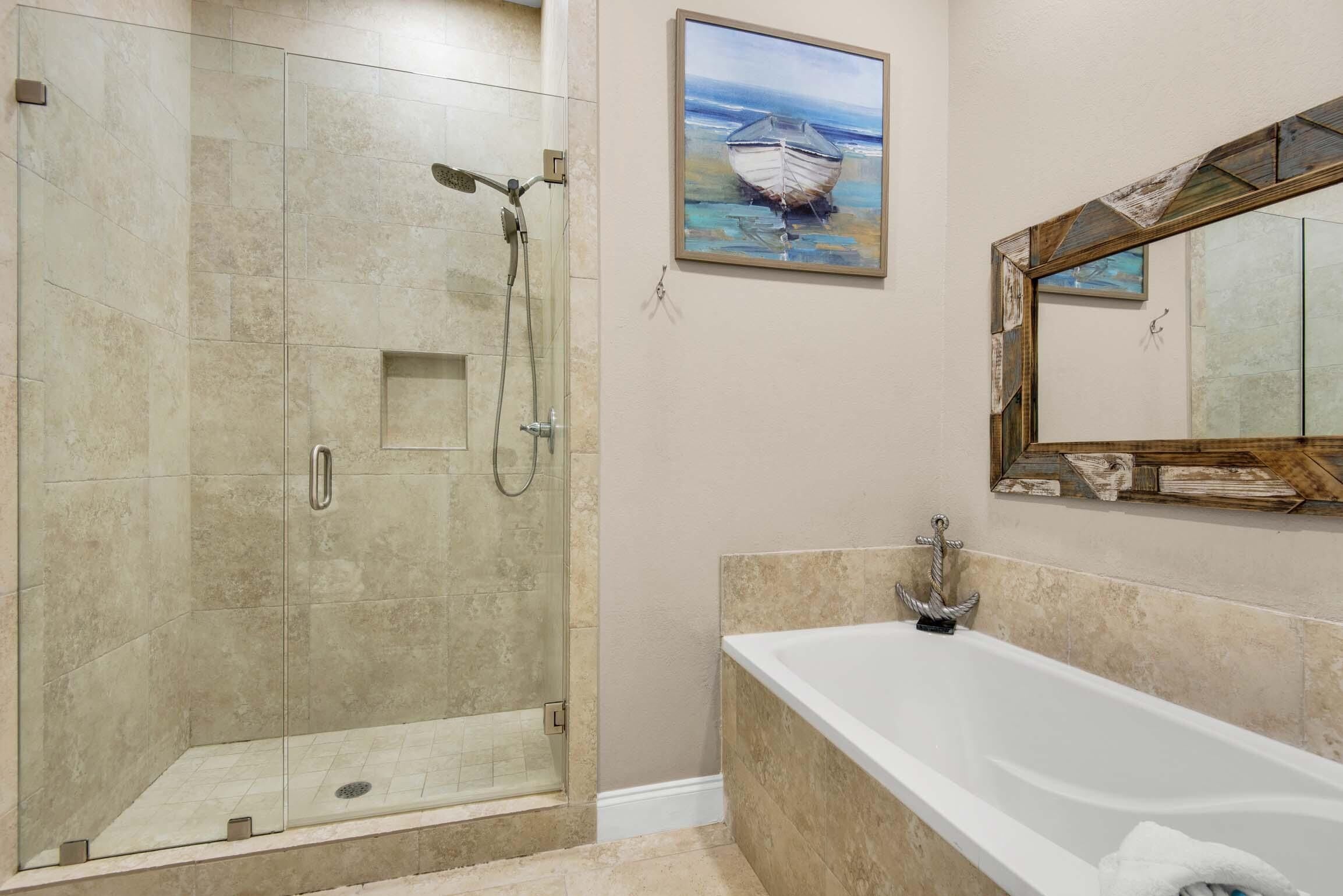 A modern bathroom with a glass-enclosed shower, a large bathtub, and a painting of a boat on the wall.