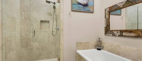 A modern bathroom with a glass-enclosed shower, a large bathtub, and a painting of a boat on the wall.
