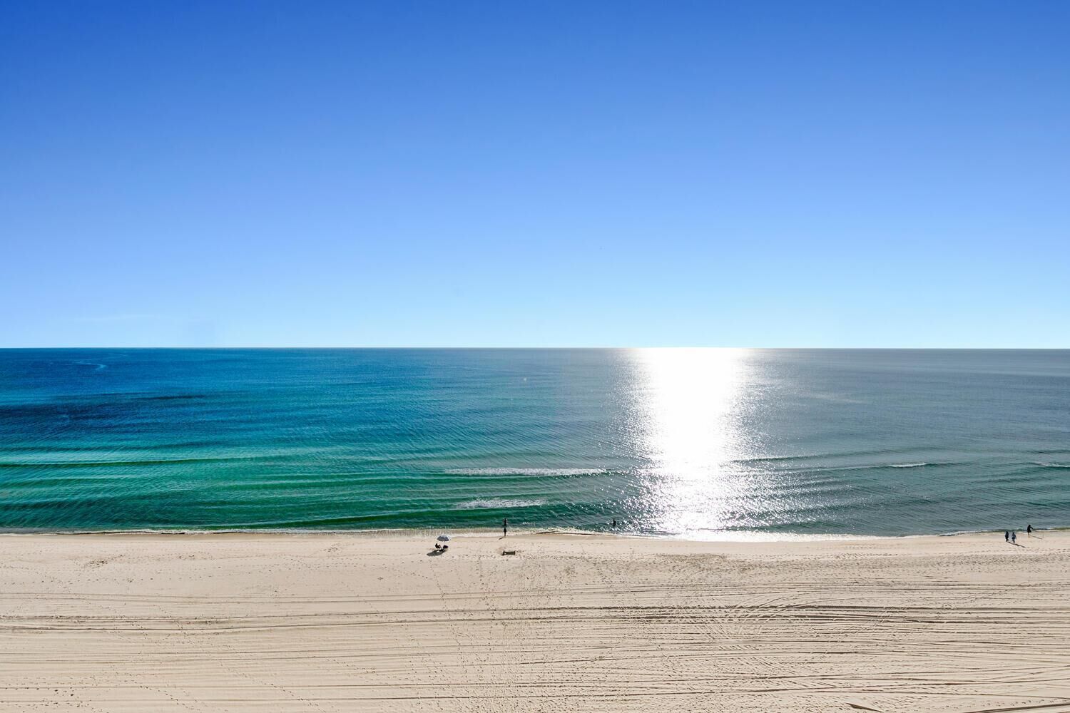 Une plage avec un ciel dégagé et une mer calme.