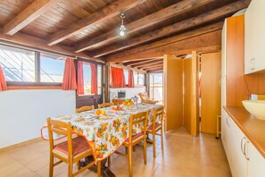 Un comedor con una mesa dispuesta para seis personas, sillas de madera, techo de madera y vistas a través de las ventanas.