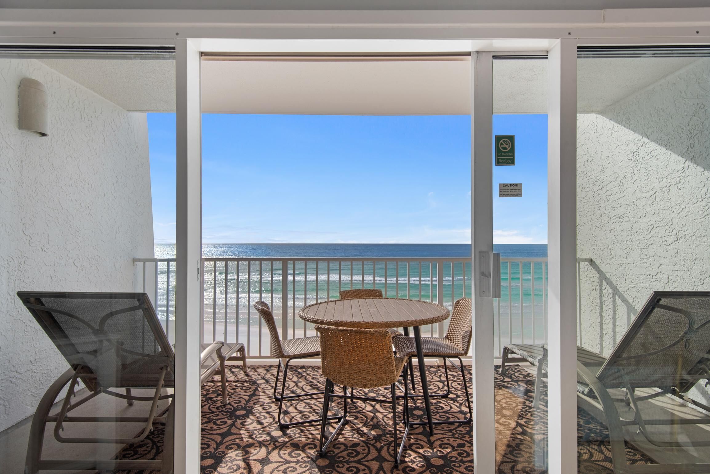 A balcony with a table and chairs, overlooking the ocean.