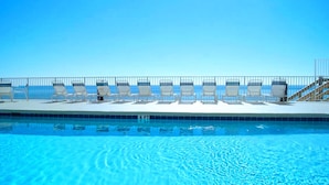 Ein Swimmingpool mit Liegestühlen und einem Metallgeländer.
