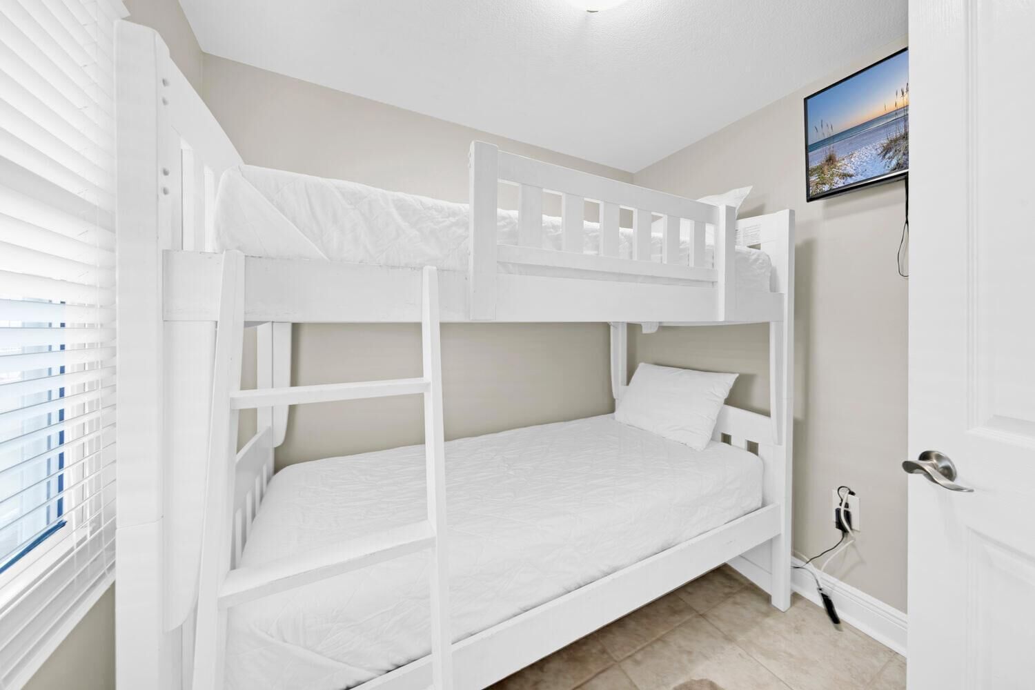 A bunk bed room with a view of the beach through the window.