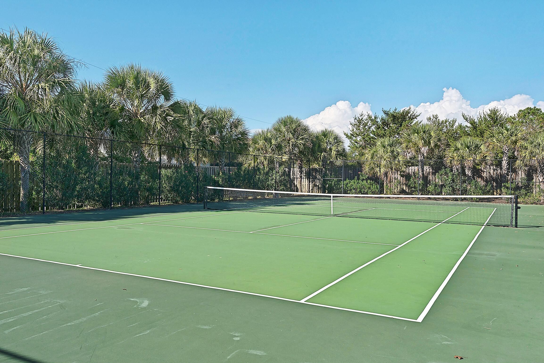 A tennis court with a net, surrounded by trees.