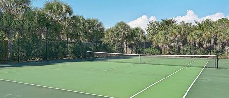 A tennis court with a net, surrounded by trees.