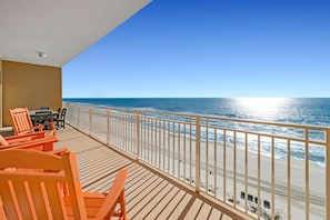 A balcony with wooden flooring, a table with chairs, and a view of the ocean. - Sterling Beach #1206 (Panama City Beach)