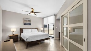 A bedroom with a bed, bedside tables, a ceiling fan, and a view through a sliding door. - East Pass 101 (Destin)