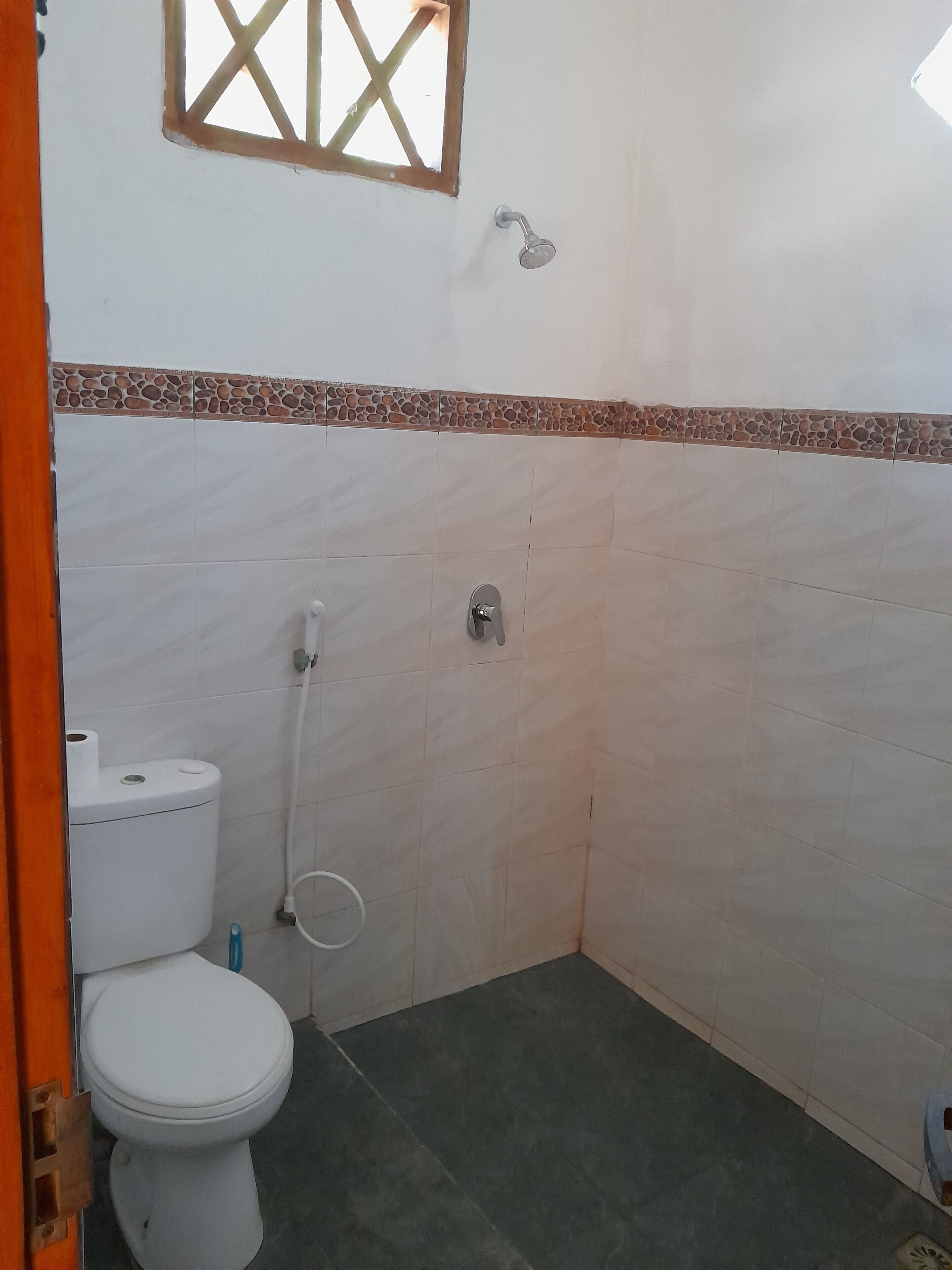 Un baño con inodoro, ducha y ventana.