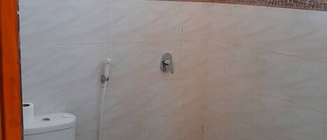 A bathroom with a toilet, a shower, and a window.