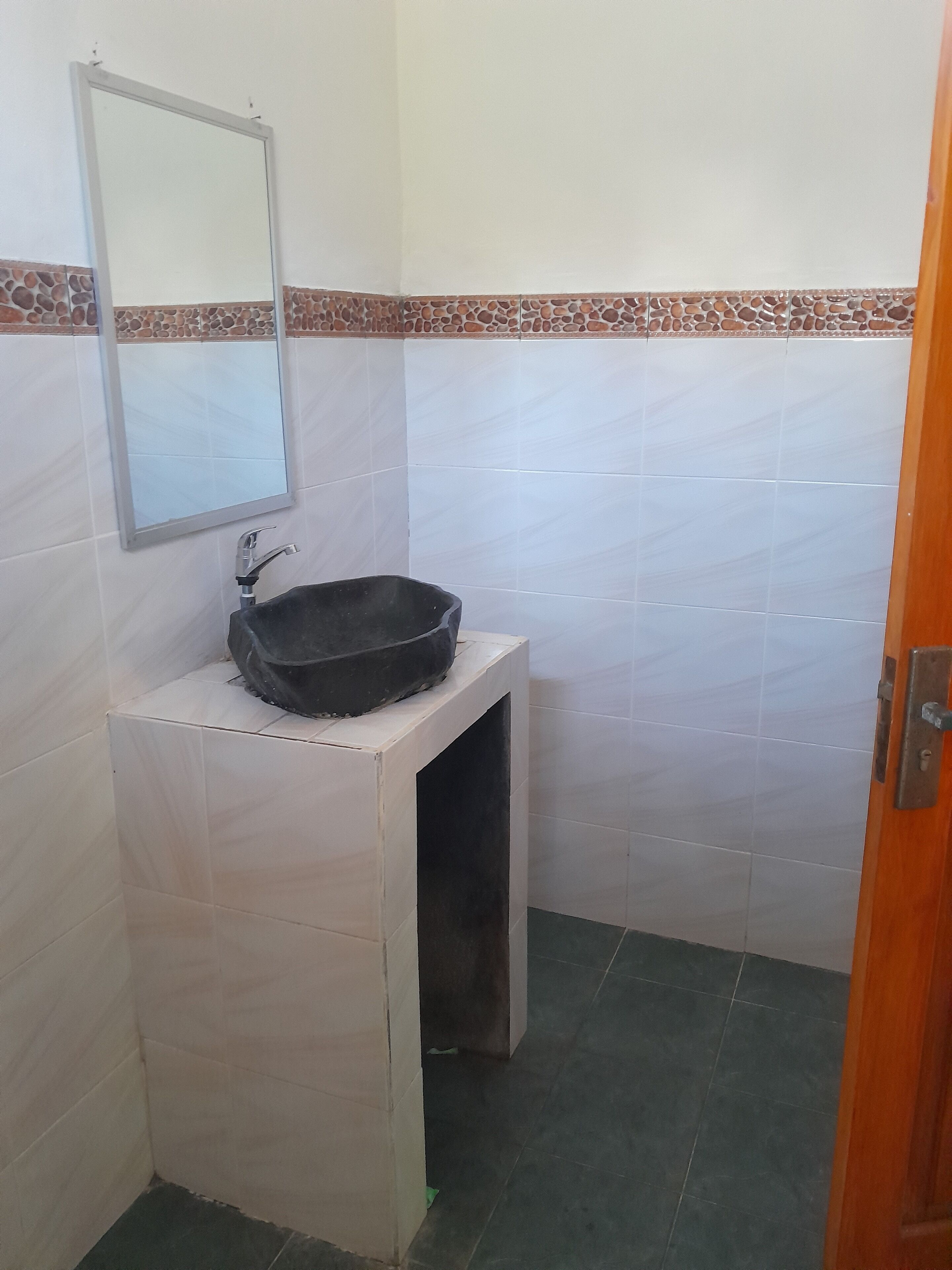 A small bathroom with a white sink, a mirror, and a tiled floor.