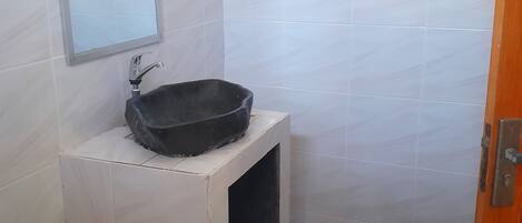 A small bathroom with a white sink, a mirror, and a tiled floor.