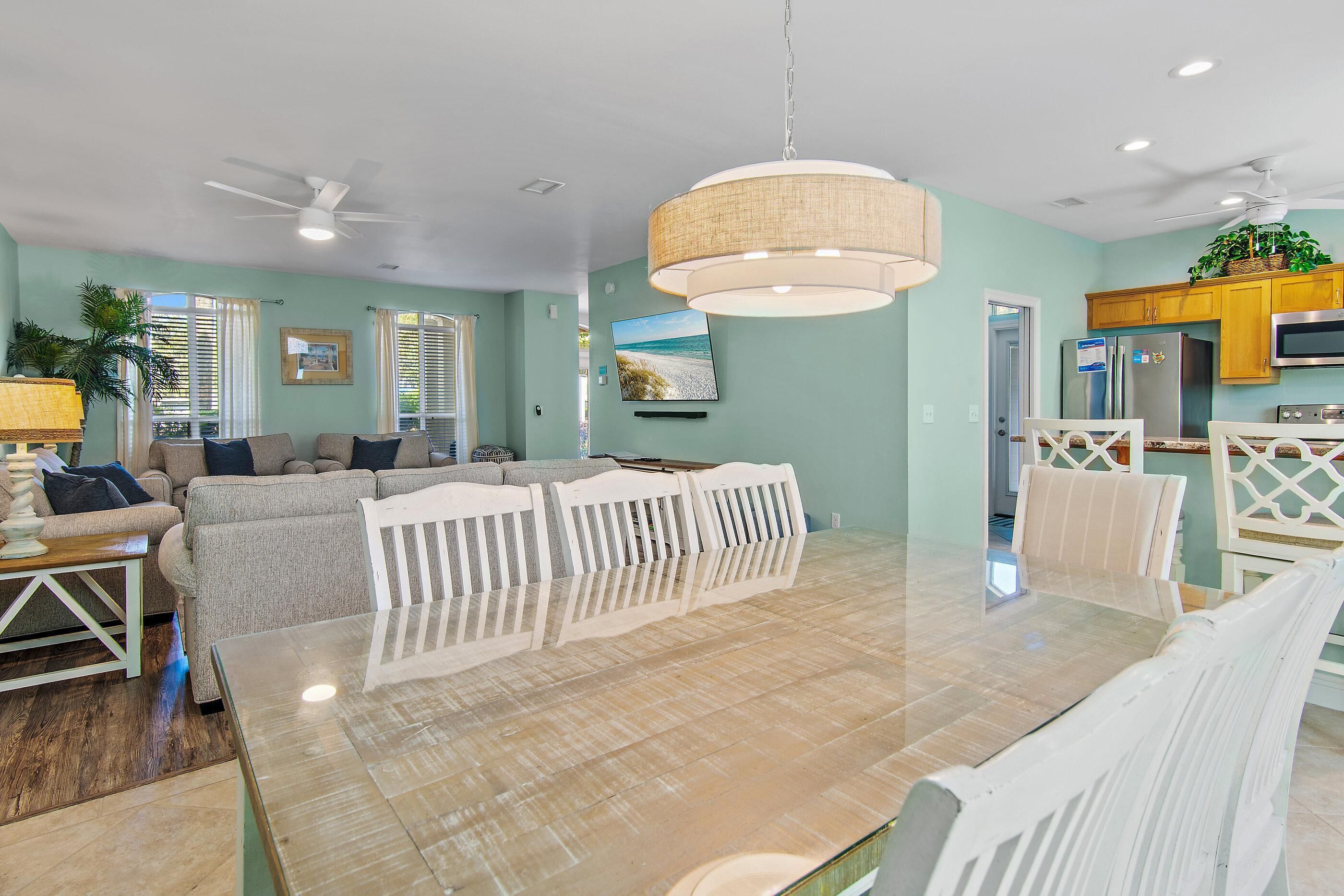 A spacious living area with a dining table, sofas, and a kitchen in the background.