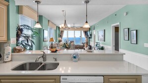 A kitchen with a large island, double sink, and pendant lighting. - Leeward Key 806 (Miramar Beach)