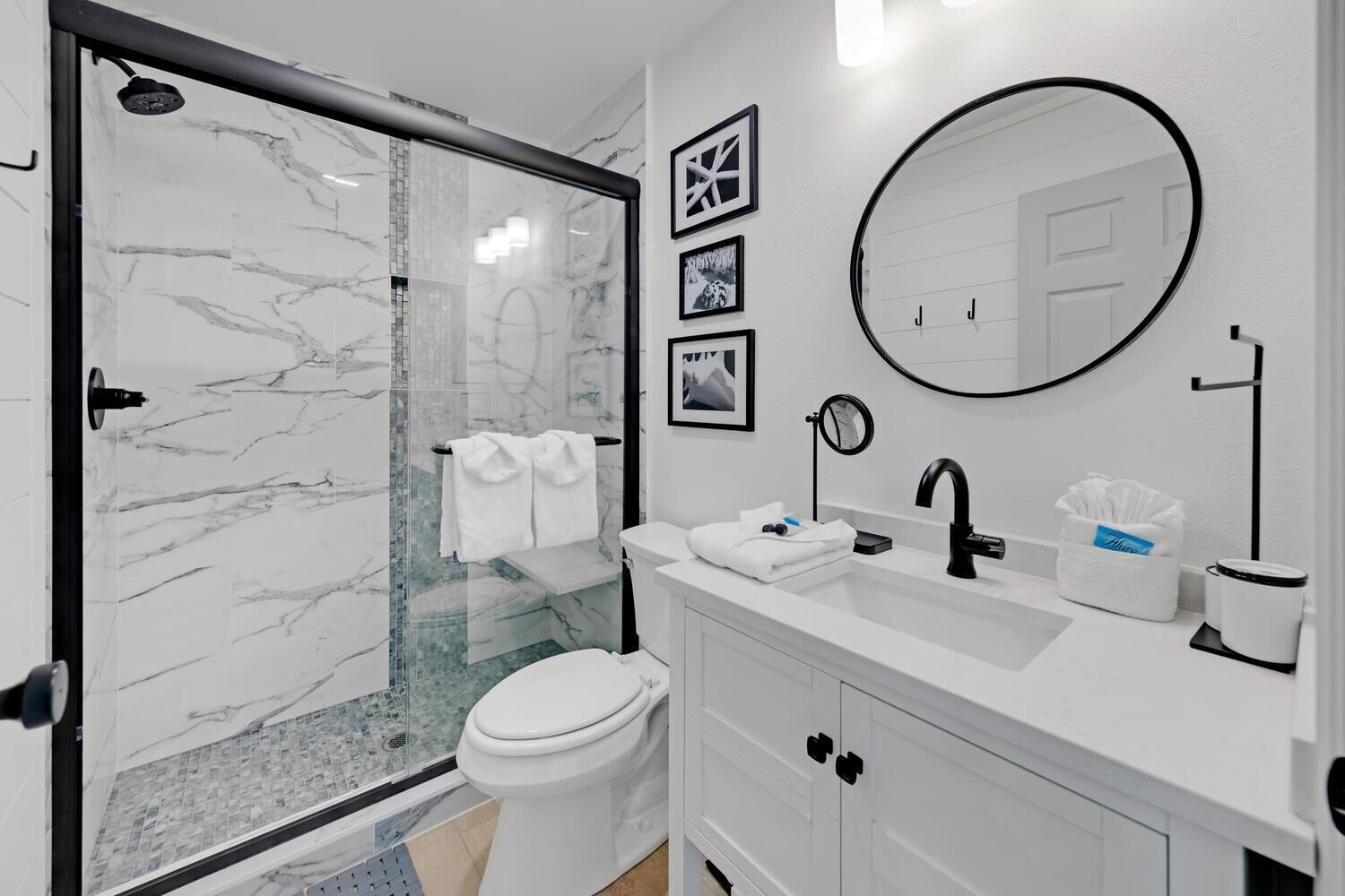 Une salle de bain moderne avec une douche à parois de verre, des toilettes, un lavabo avec un miroir et un porte-serviettes.