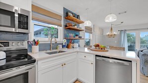 A modern kitchen with white cabinetry, stainless steel appliances, and a central island. - Beachside Villas 1123- A Sandy Carol (Santa Rosa Beach)