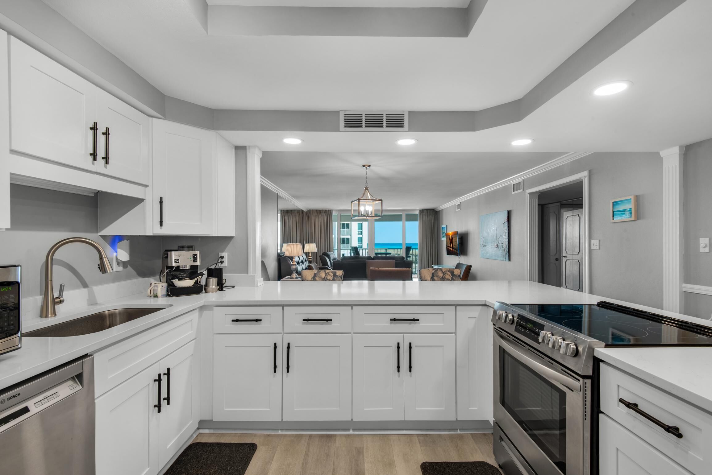 A modern kitchen with white cabinetry, a built-in oven, and a large island with a sink.