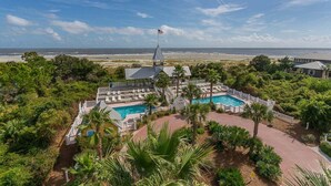 A resort with a pool, palm trees, and a view of the beach. - Ebb Tide, Steps from the Beach & Community Pool (Saint Simons Island)