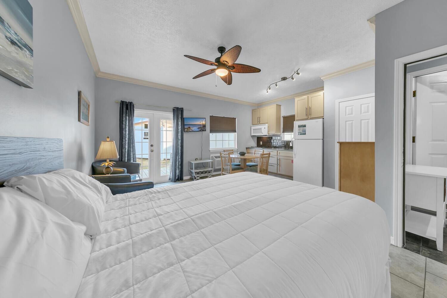 Une chambre dotée d’un grand lit, d’un ventilateur de plafond, d’un bureau et d’une kitchenette.