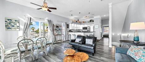 A spacious living area with a modern kitchen, a dining area with wicker chairs, and a balcony with a view.