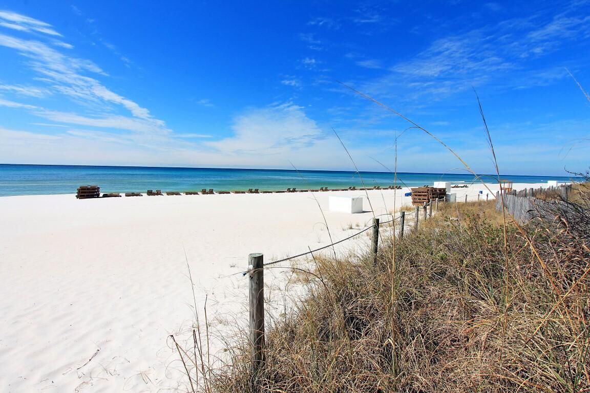 A beach with a sandy shore, wooden structures, and a clear blue sky.