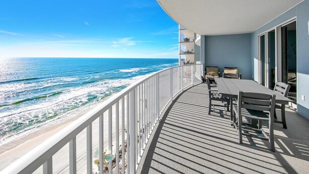 Un balcon avec vue sur l’océan, une table avec des chaises et une balustrade blanche.
