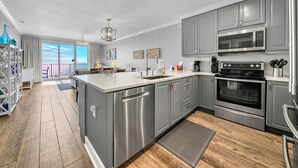 Une cuisine moderne avec des meubles gris, des appareils en acier inoxydable et un grand îlot central.