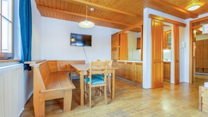Un coin repas en bois avec un banc et des chaises, un téléviseur fixé au mur et un plafond en bois.
