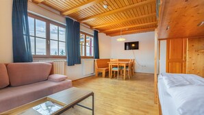 Une pièce chaleureuse avec un plafond en bois, un canapé, une table à manger avec des chaises et un lit.