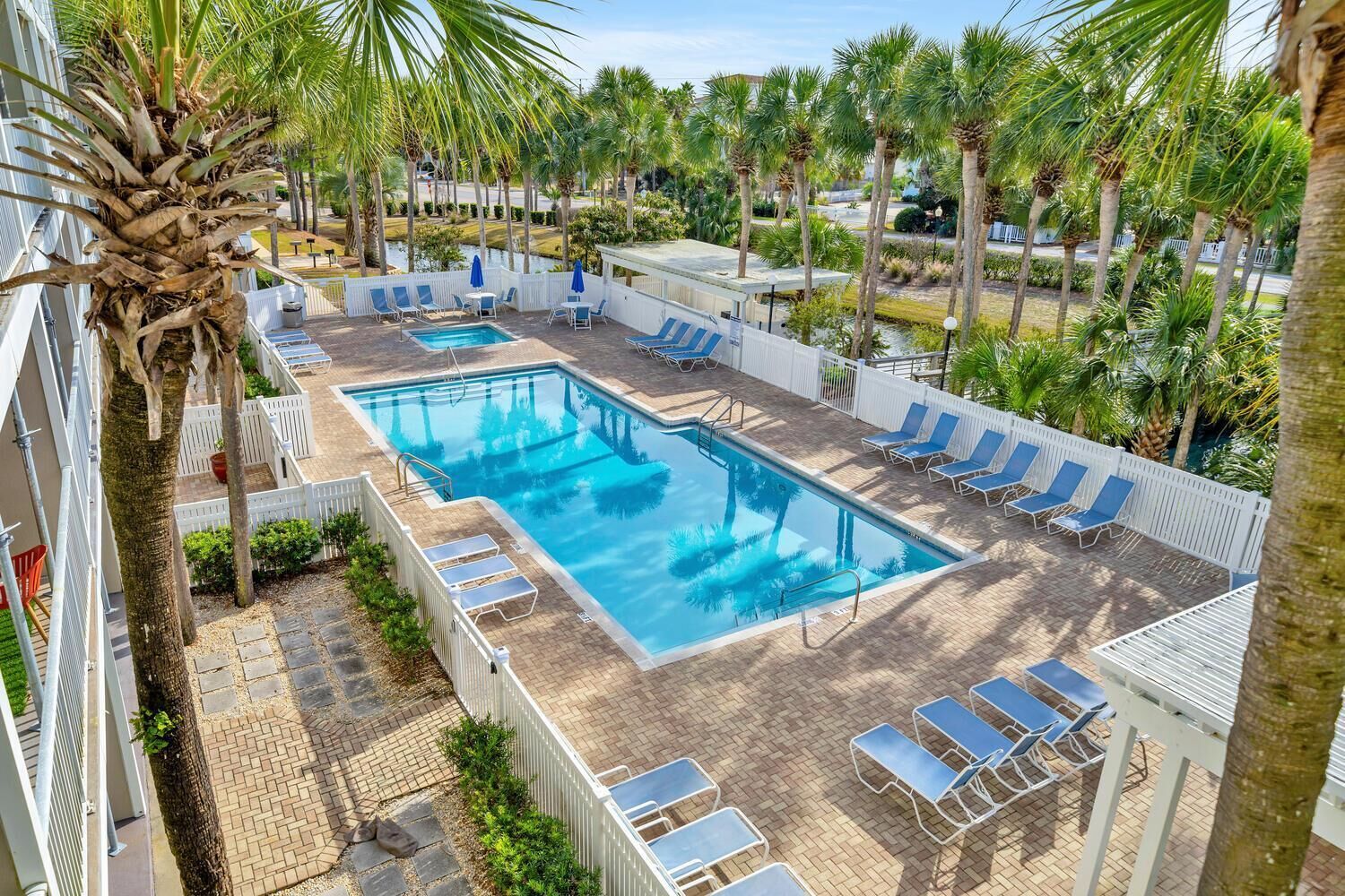 A rectangular pool with blue water, surrounded by white fences and blue lounge chairs.