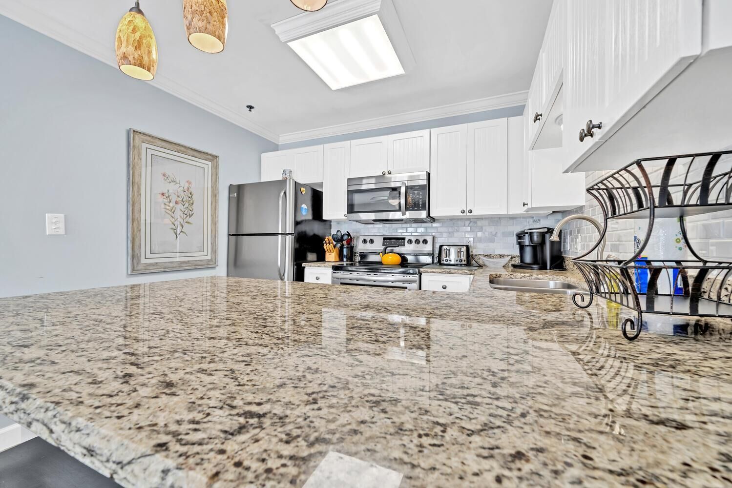 A modern kitchen with granite countertops, stainless steel appliances, and white cabinetry.