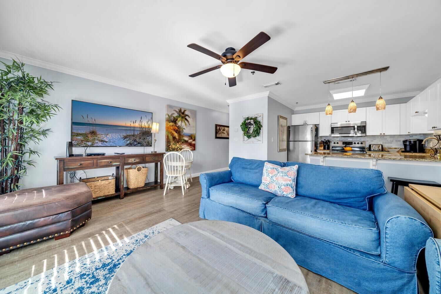 Un salon moderne avec un canapé bleu, une table basse en bois et un ventilateur de plafond.