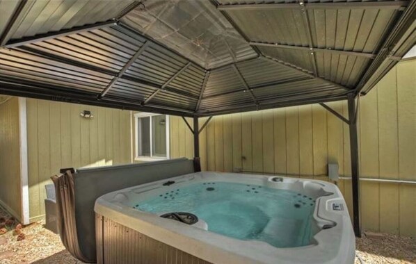 A hot tub under a metal roof structure.