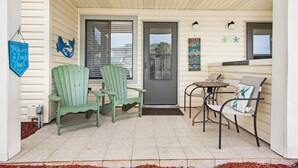 En veranda med to grønne Adirondack-stole, et lille bord og en bænk.