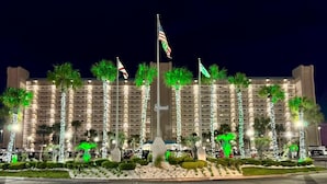 A hotel with multiple floors, palm trees, and flags.