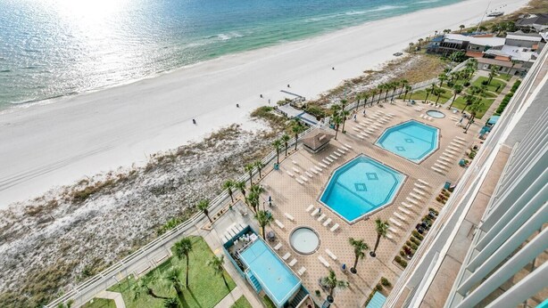 A resort with a beach view, multiple swimming pools, and a well-maintained lawn area.
