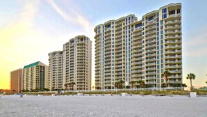A beachfront hotel with multiple high-rise buildings, a sandy beach in the foreground, and palm trees. - Silver Beach Towers 603 East (Destin)