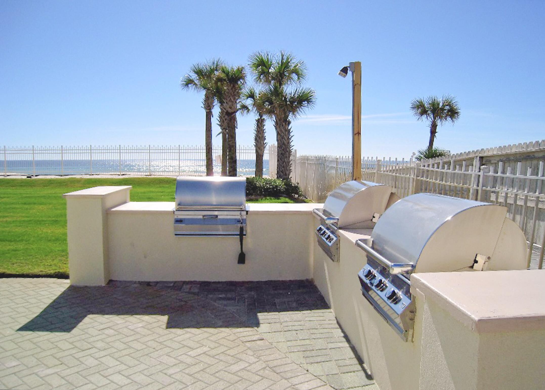 Un espace barbecue extérieur avec vue sur la plage et les palmiers.