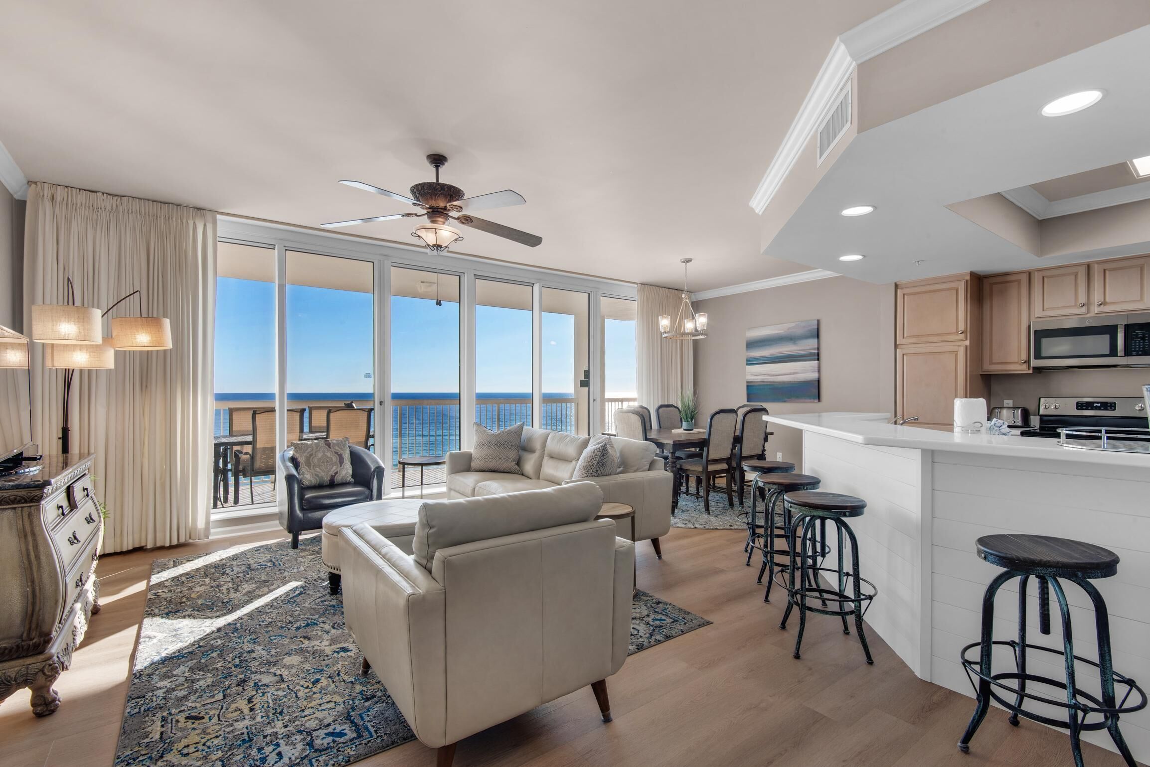 A spacious living area with a large sofa, a dining table, and a kitchen with a bar.