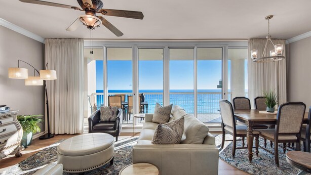 A spacious living room with a large window, a ceiling fan, and a dining area with a view of the ocean. - Silver Beach Towers 603 East (Destin)