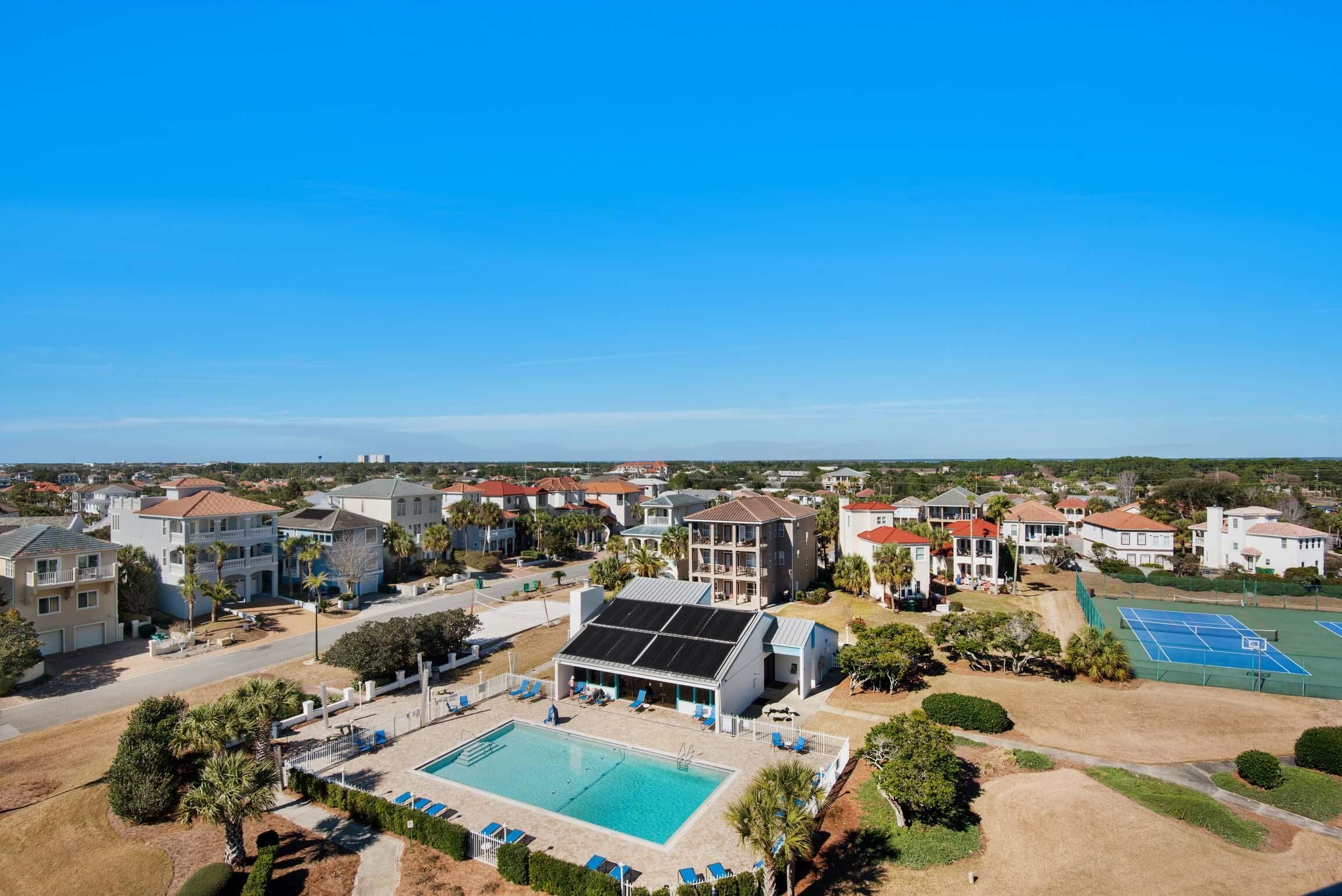 A residential area with a swimming pool, tennis courts, and a building with solar panels.