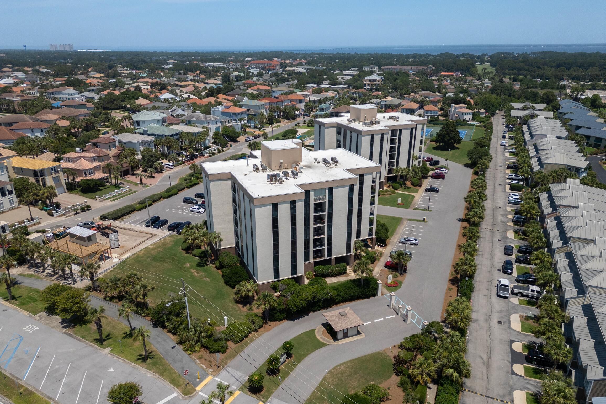 An aerial view of a residential area with modern buildings, a parking lot, and a clear sky.