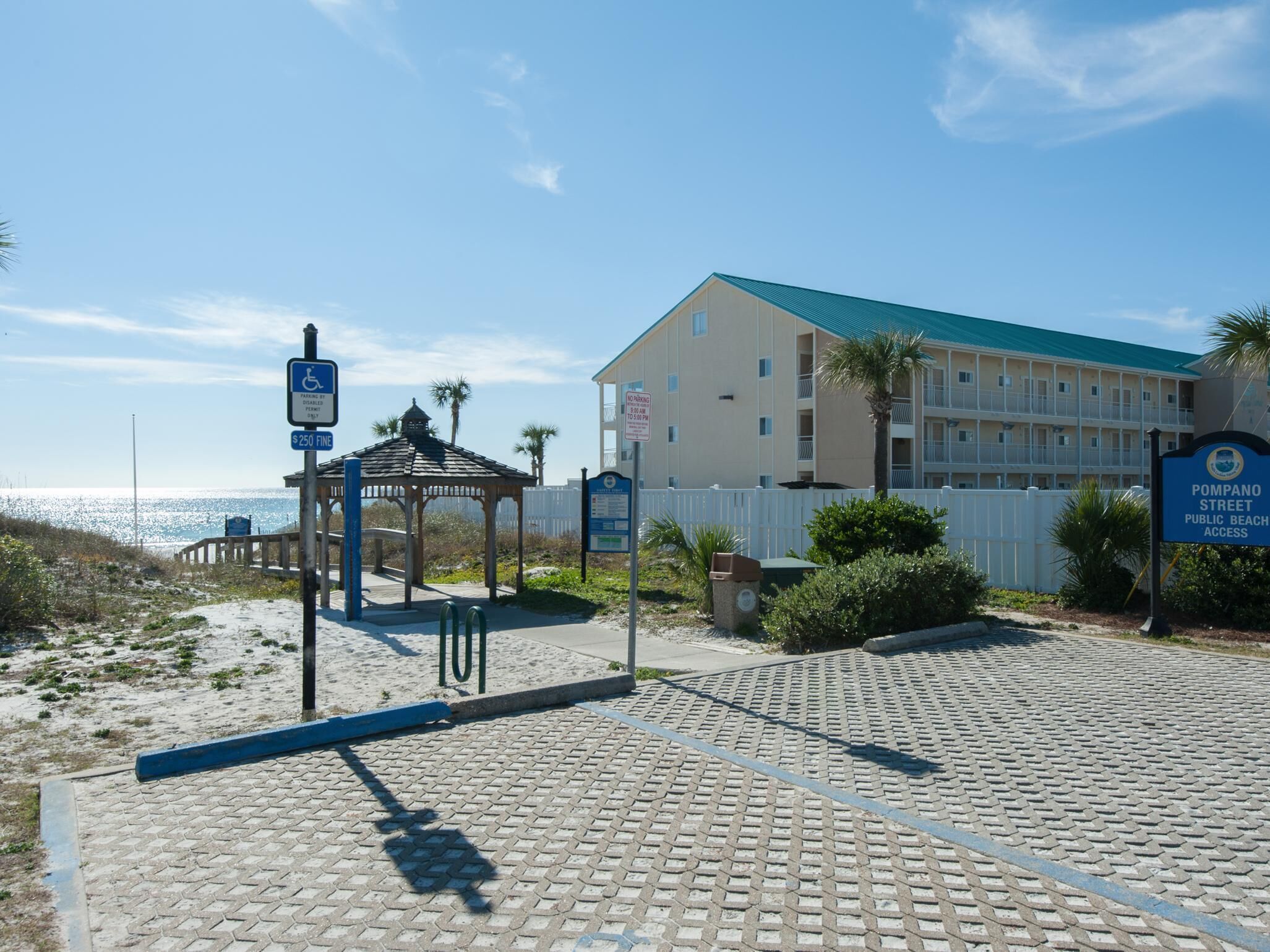 A beachside building with a wheelchair-accessible entrance, a gazebo, and a sign indicating public beach access.