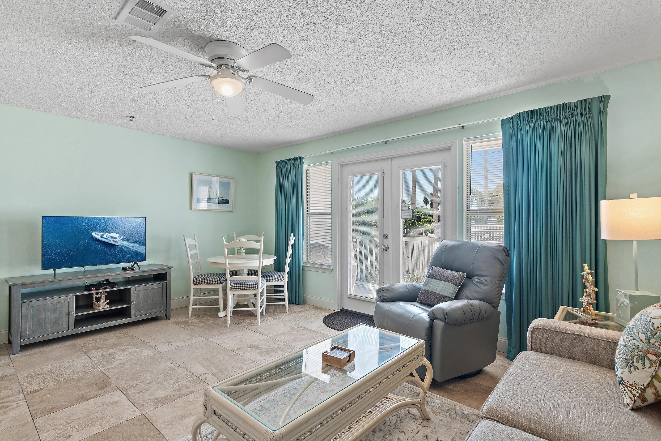 A living room with a television, a glass coffee table, a sofa, and a chair.